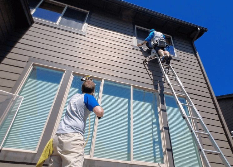 People cleaning windows. 
	One person on the ground, one person on a ladder