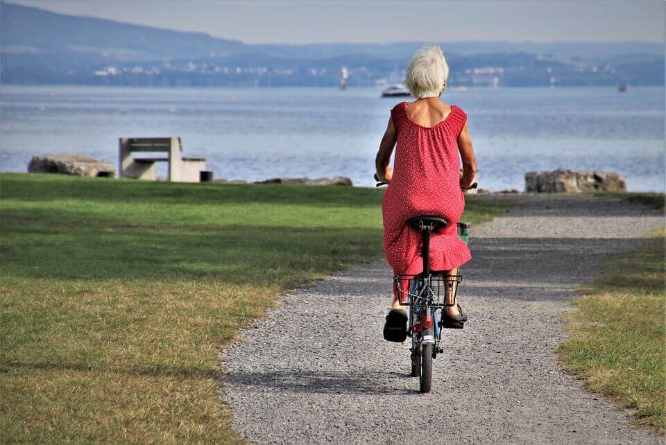 Person with a red dress biking along the ocean.