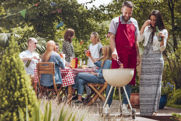 People eating at a atable. Two people barbecueing.