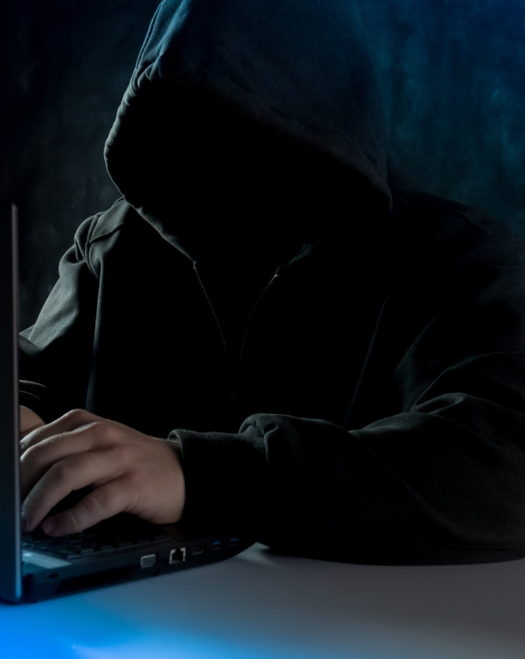 Person in black hoodie using a laptop computer.
