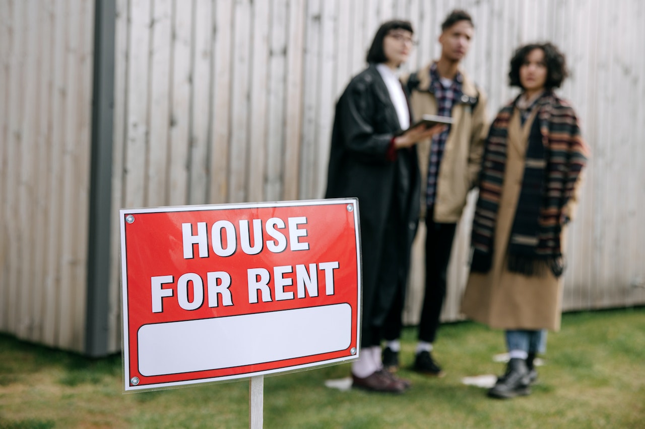 House for rent sign, 3 people standing in the background