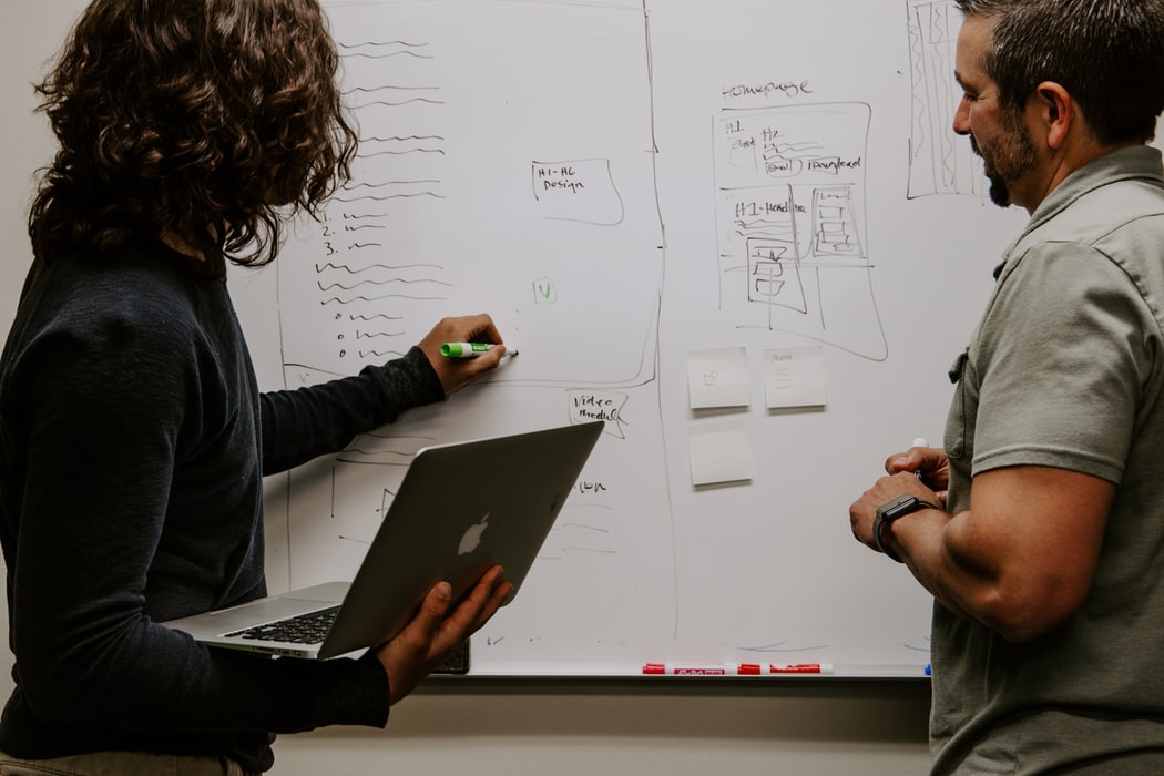 2 people writing on a white board.