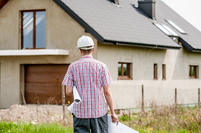 Architect with plans in his hands looking at a house