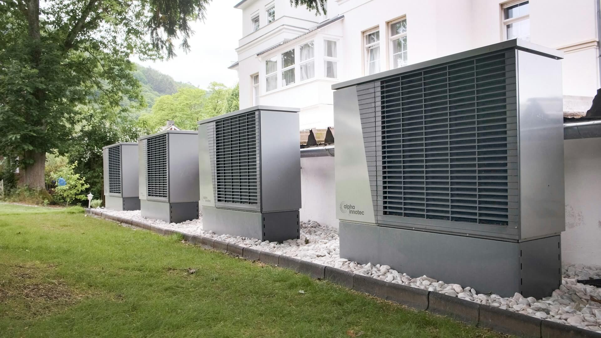 Four industrial air conditioning units lined up outside a building. Image via Unsplash