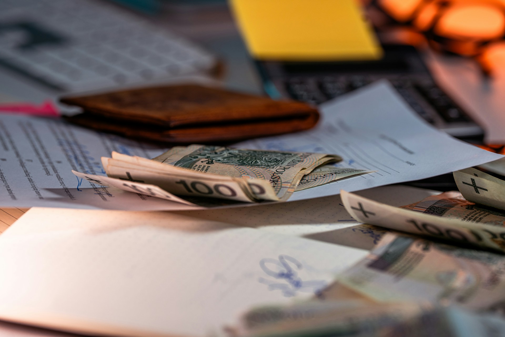 Money and utility bill documents on a desk. Image via Unsplash