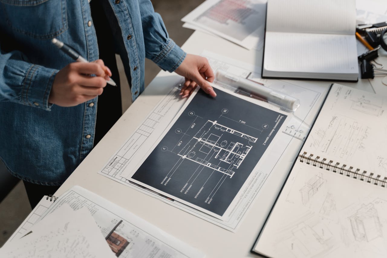 Person in a denim jacket looking at construction plans. Image by Pexels