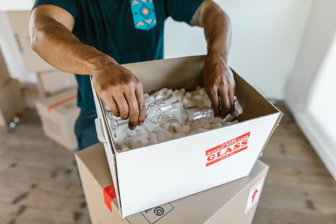 person packing fragile items in a box