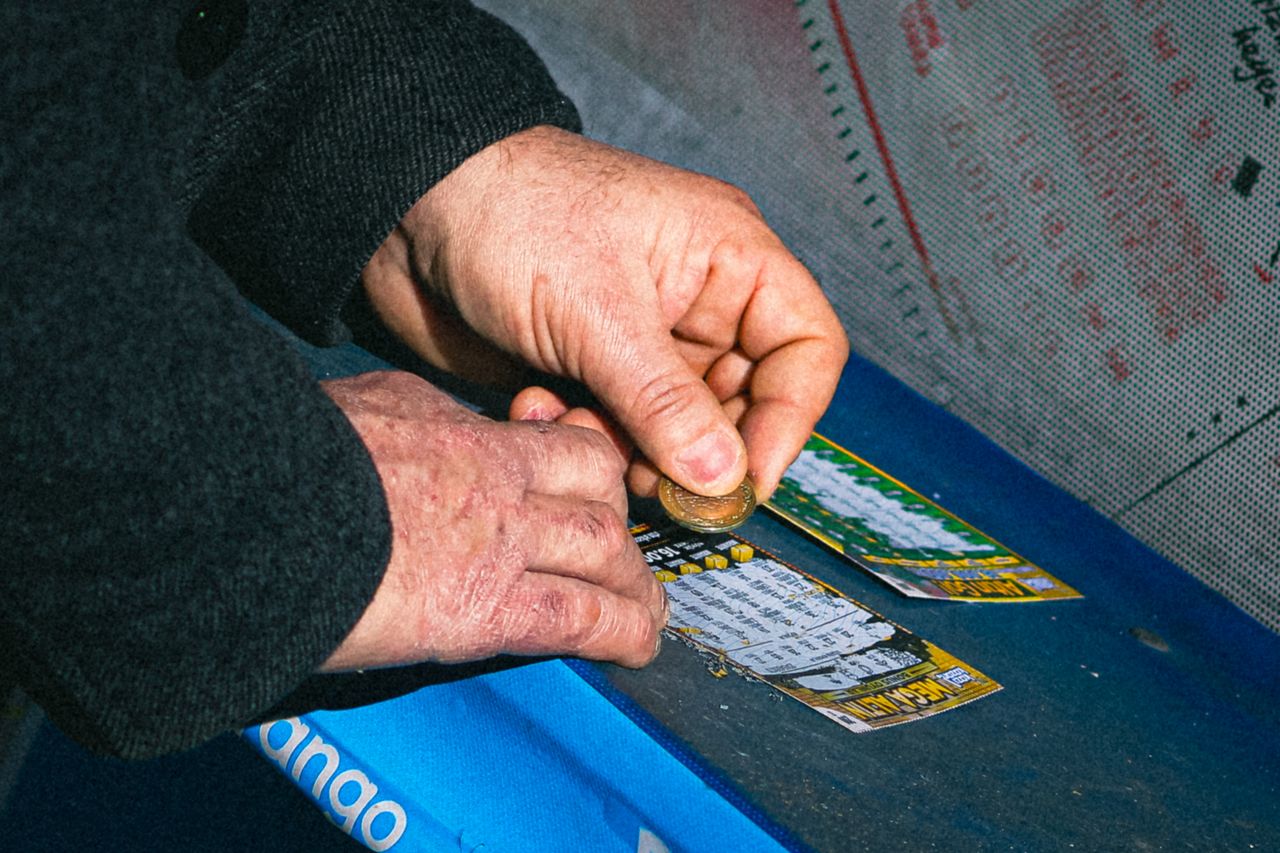 Close up of hands scratching custom promotional lottery-style tickets. Image via Pexels