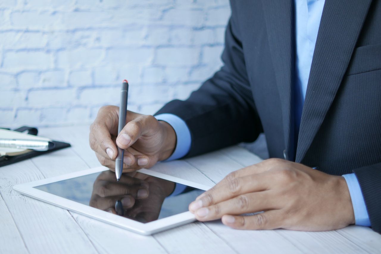 Person signing a PDF document electronically on a tablet. Image by Pexels