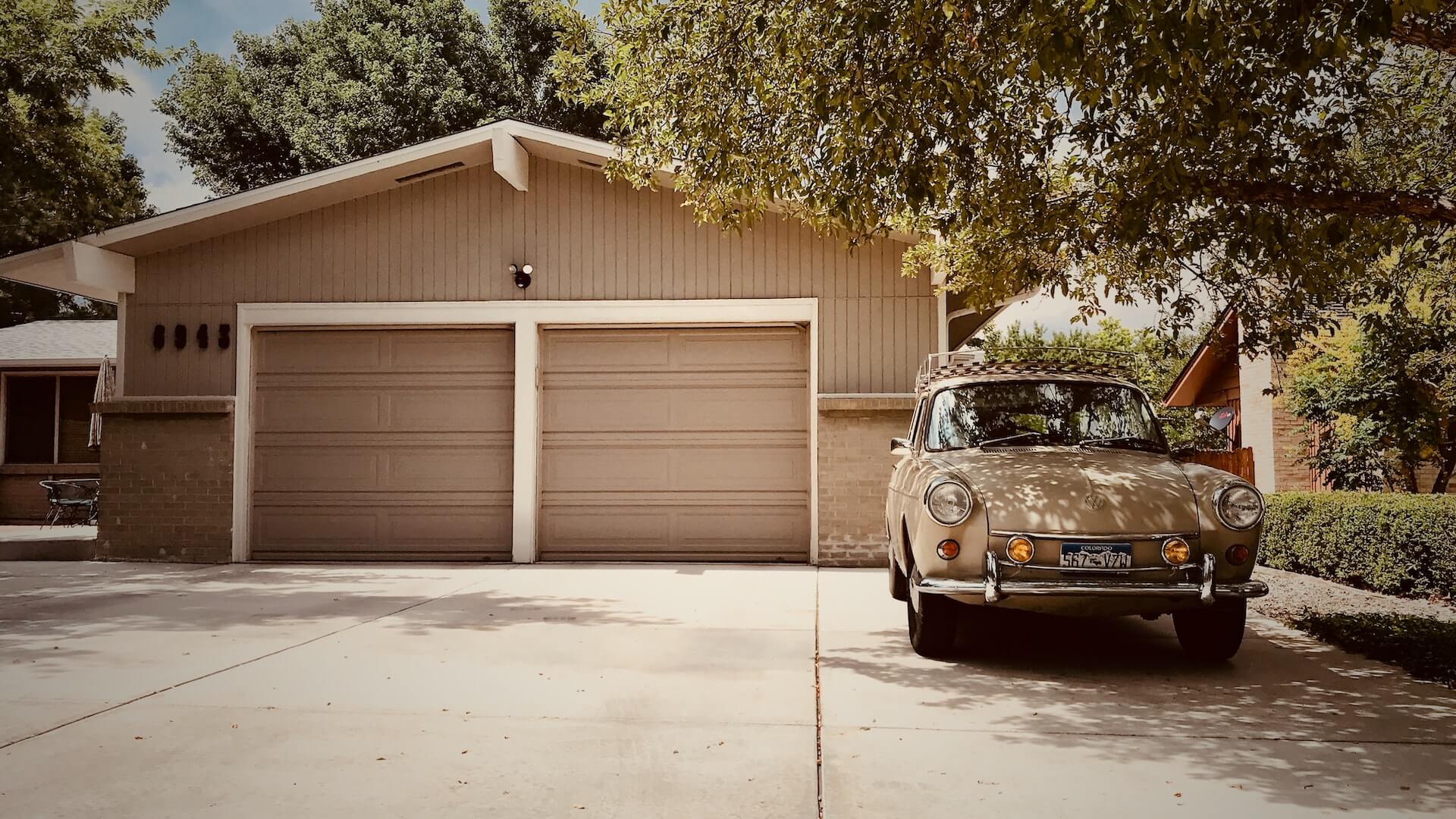 old car sitting in driveway in front of a 2 car garage