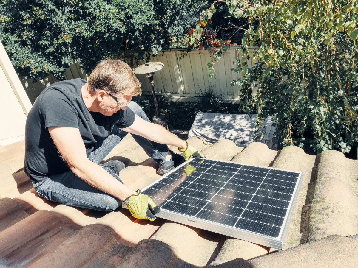 Person installing solar panels on a roof. Image by Pexels