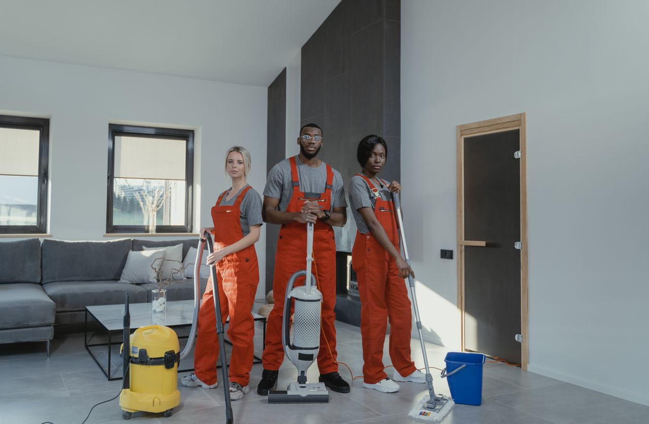 Cleaners in orange uniform preparing to clean a home. Image by Pexels