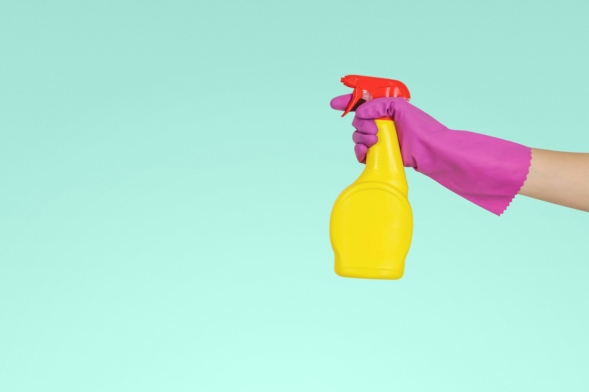 Person with a purple glove holding a yellow spray bottle. Image by Unsplsh