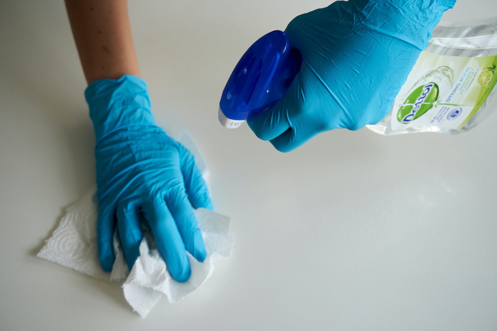 person with gloves using a spray bottle to clean