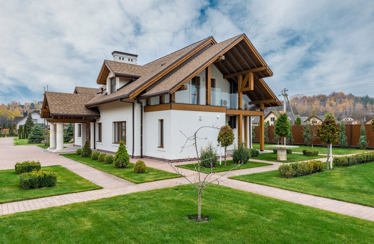 White villa with newly mowed green lawn and trees and bushes in the yard. Image by Pexels