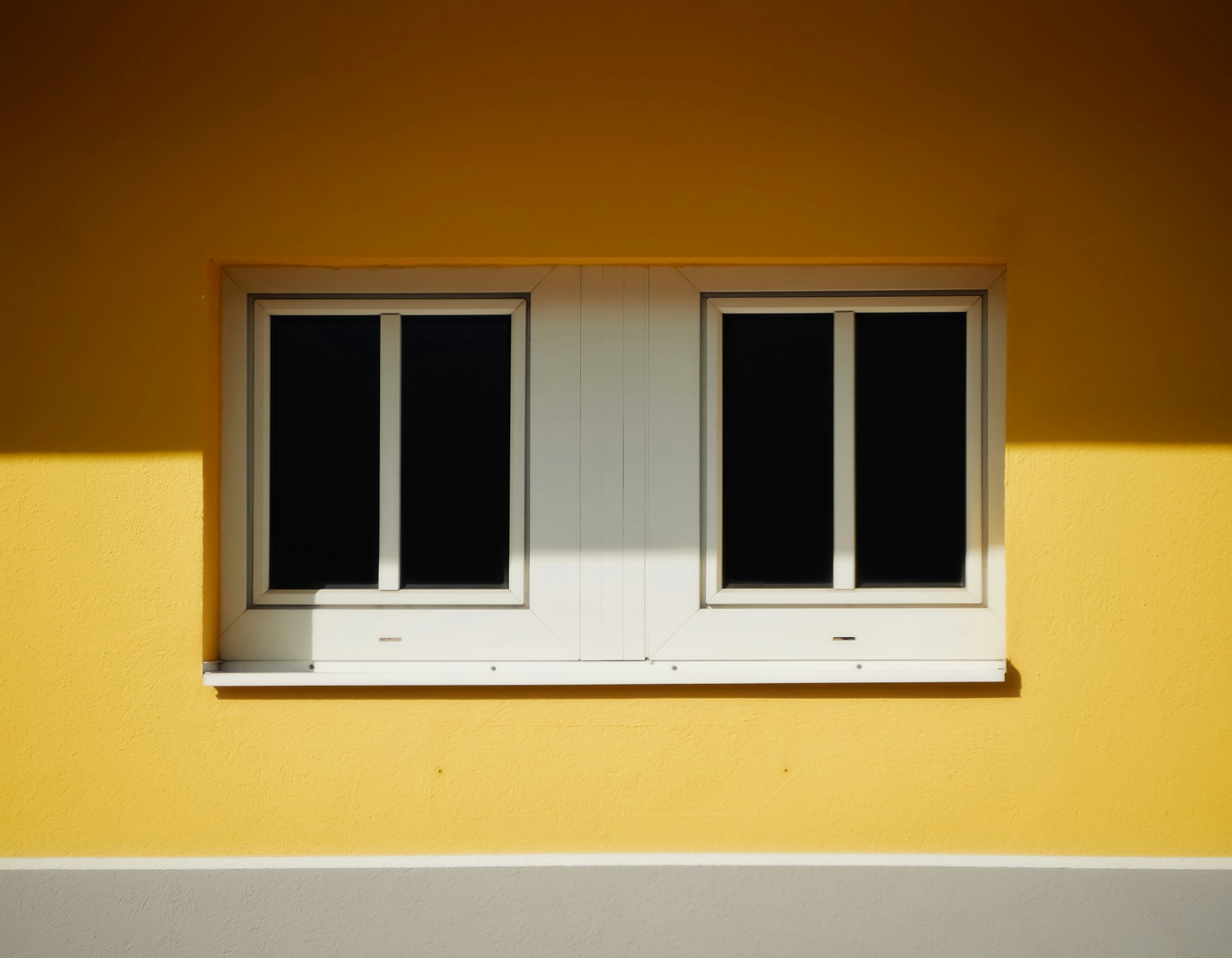 White wooden framed glass windows on a yellow house. Image by Unslash.