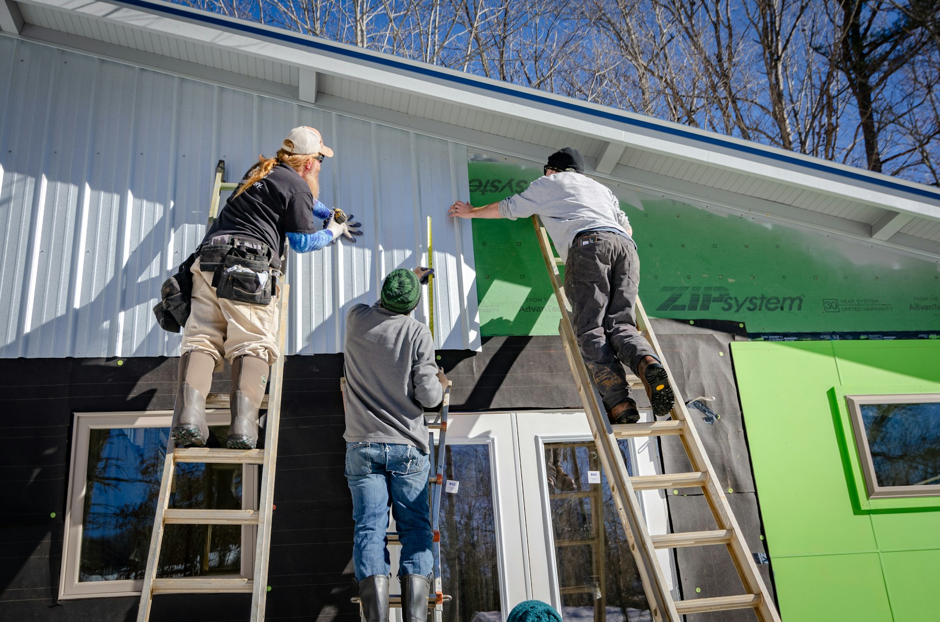 Contractors putting siding on a house. Image by Unsplash