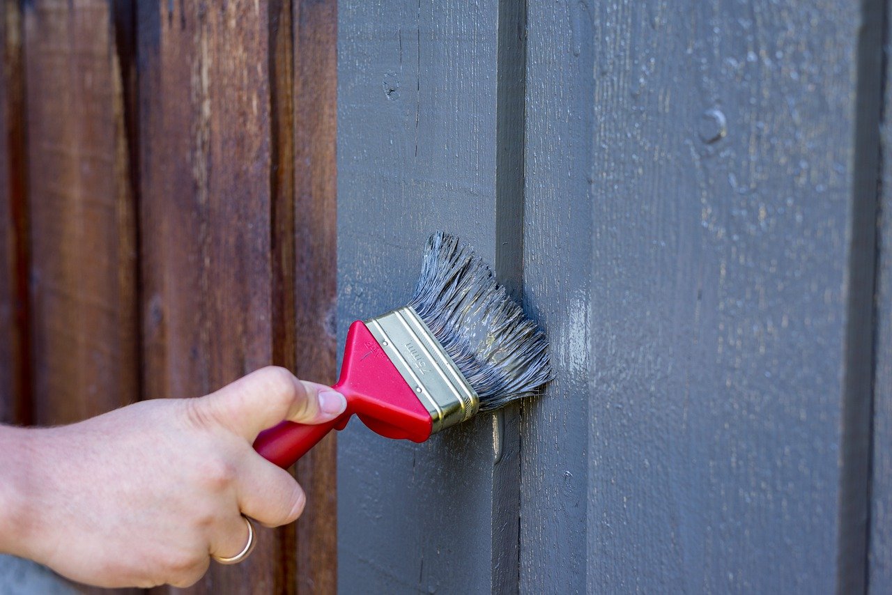 Person painting a fence grey. Image by Pixabay