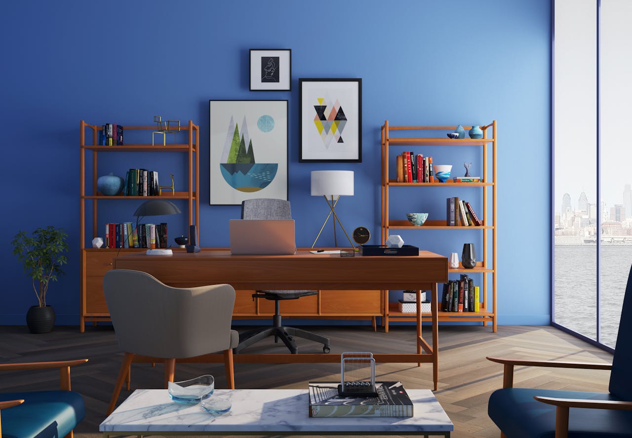 Brown office furniture, blue walls, art on wall, large floor to ceiling windows. Image by Pexels