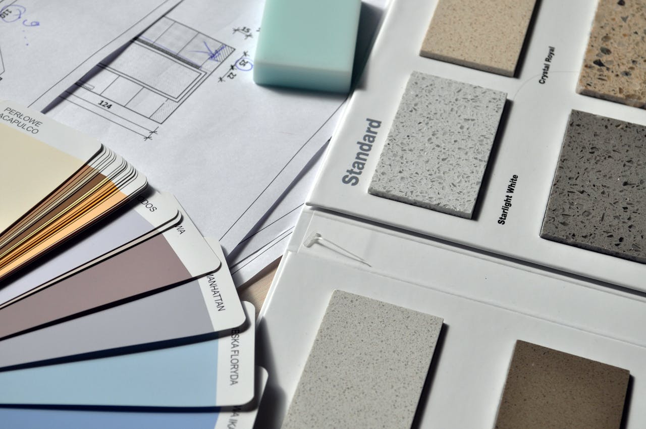 Gray standard color book near green eraser, floorplans. Image by Pexels