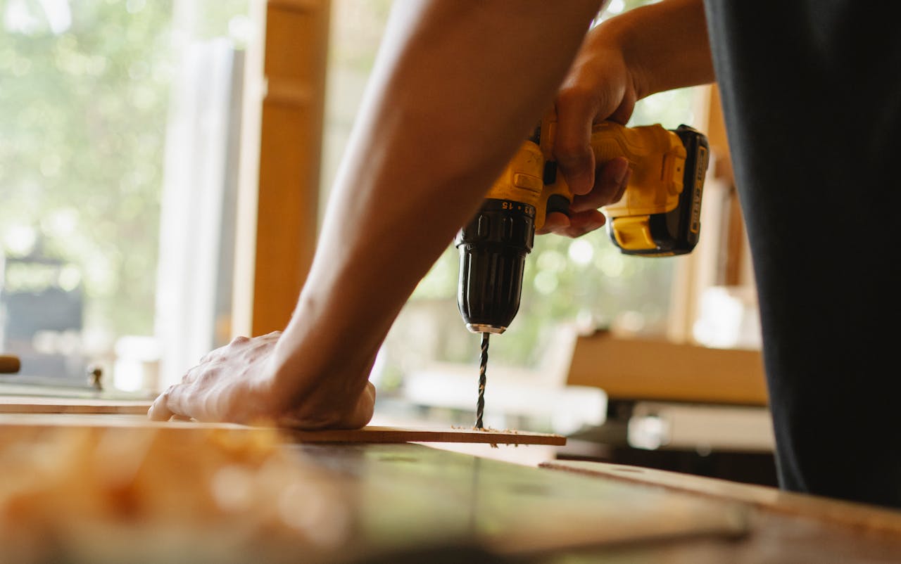 Man drilling wooden plank on desk. Image by Pexels