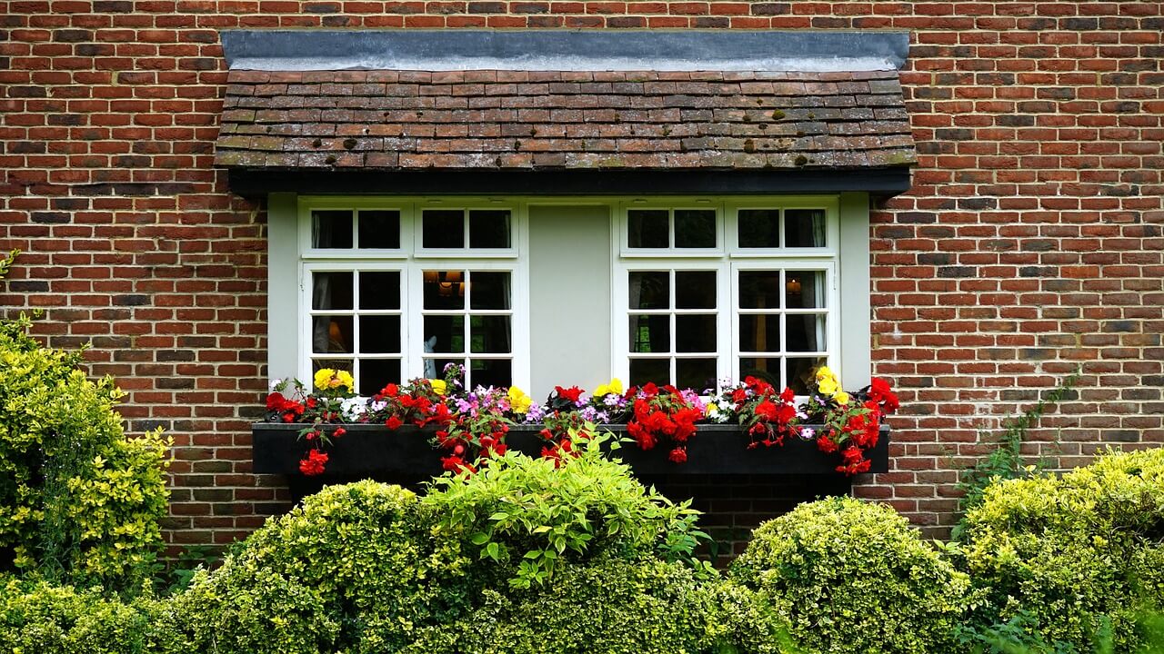 Brick house with 2 windows and plantboxes. Image by Pixabay