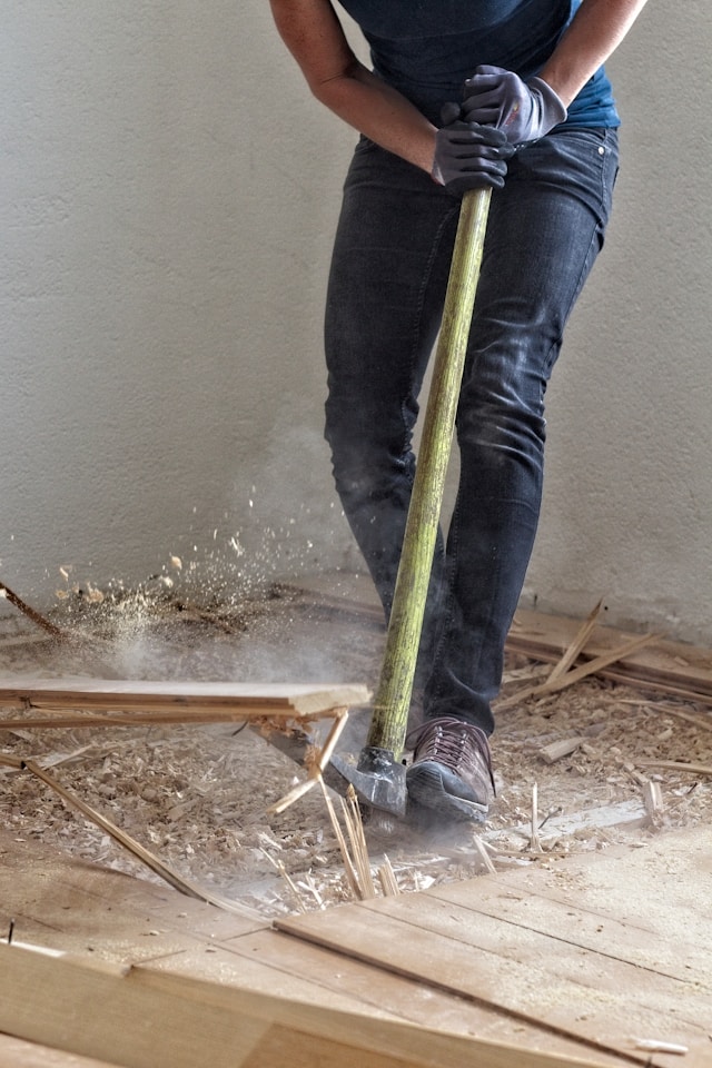Property owner holding a large hammer inside a rental unit during a strategic renovation. Image via Unsplash