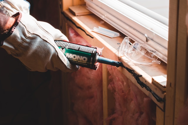 Person caulking a window. Image by Unsplash