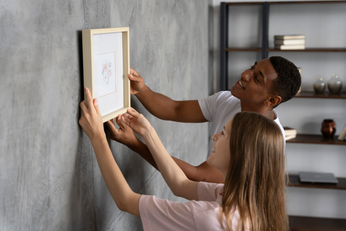 Two people haning a painting on the wall