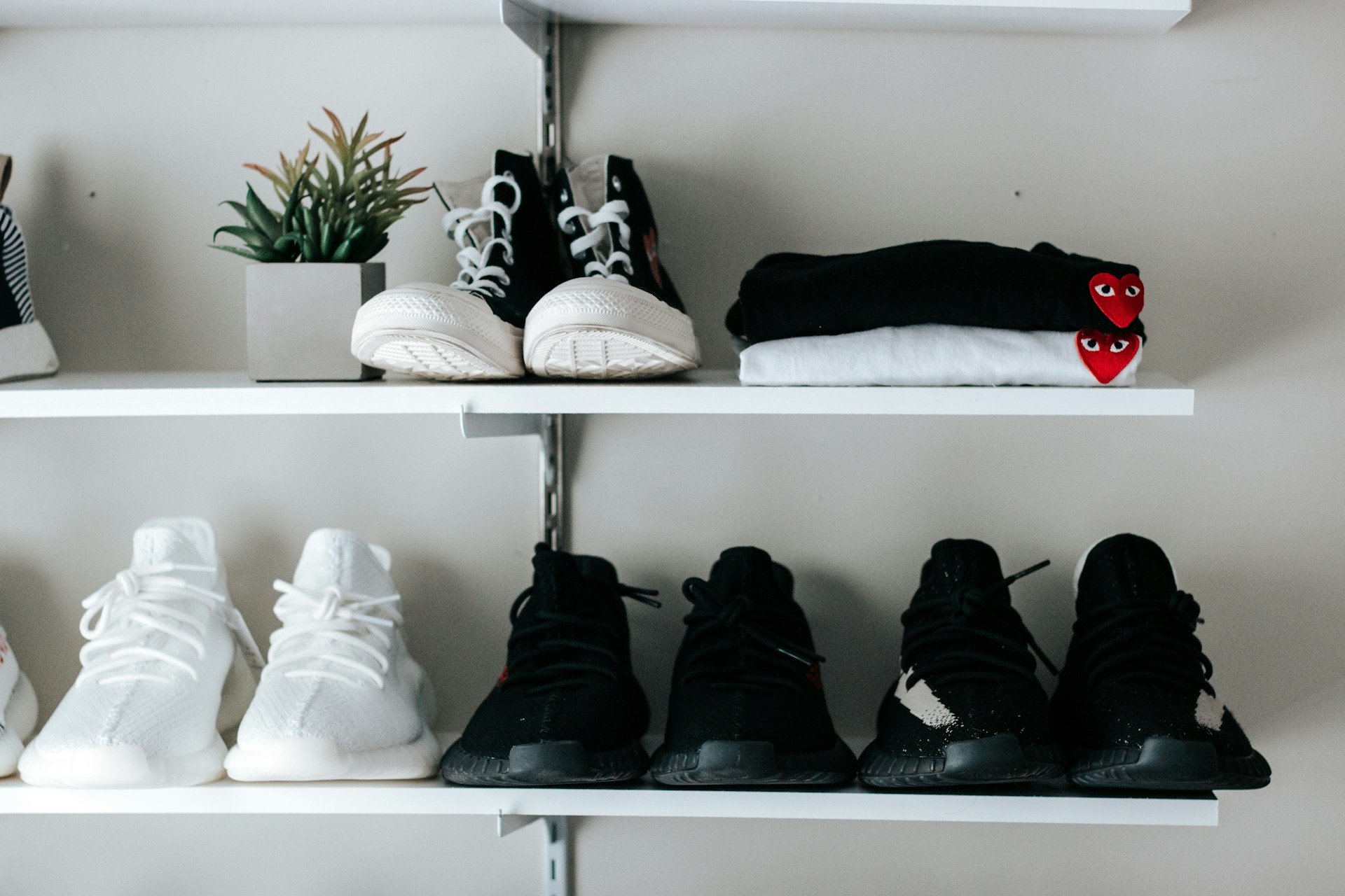 Black and white shoes sitting on white floating shelves. Image by Unsplash.