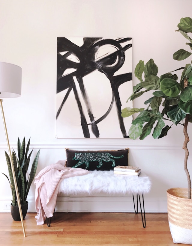 Bench, plants on floor, wall art. Image by Unsplash