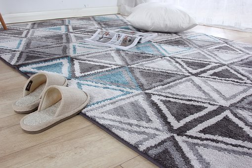 Rug on hardwood floors, slippers, pillow and magazine on the rug.