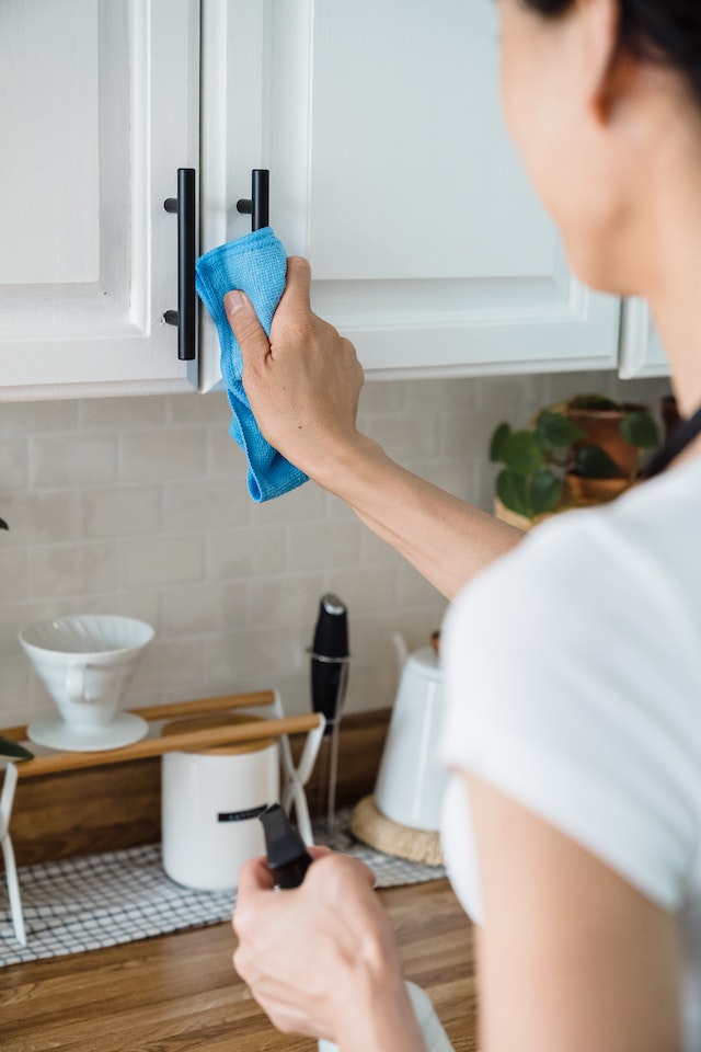 Person cleaning kitchen cabinets