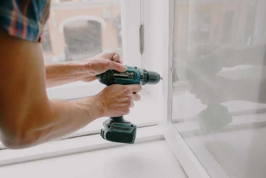 Person drilling into wood next to a window