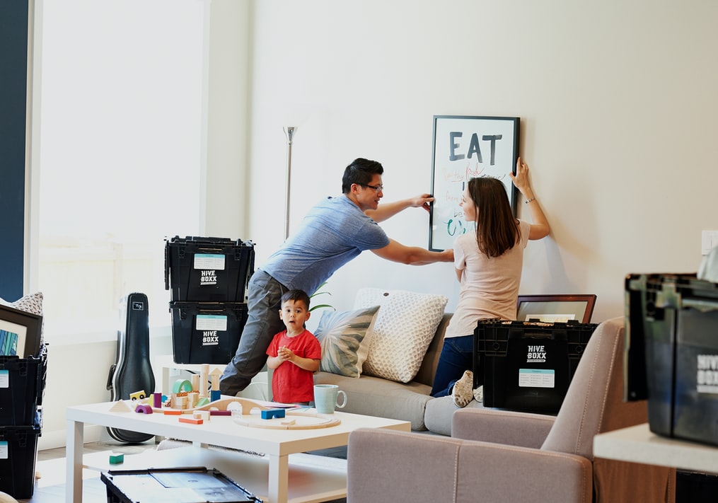 2 people hanging art on a wall