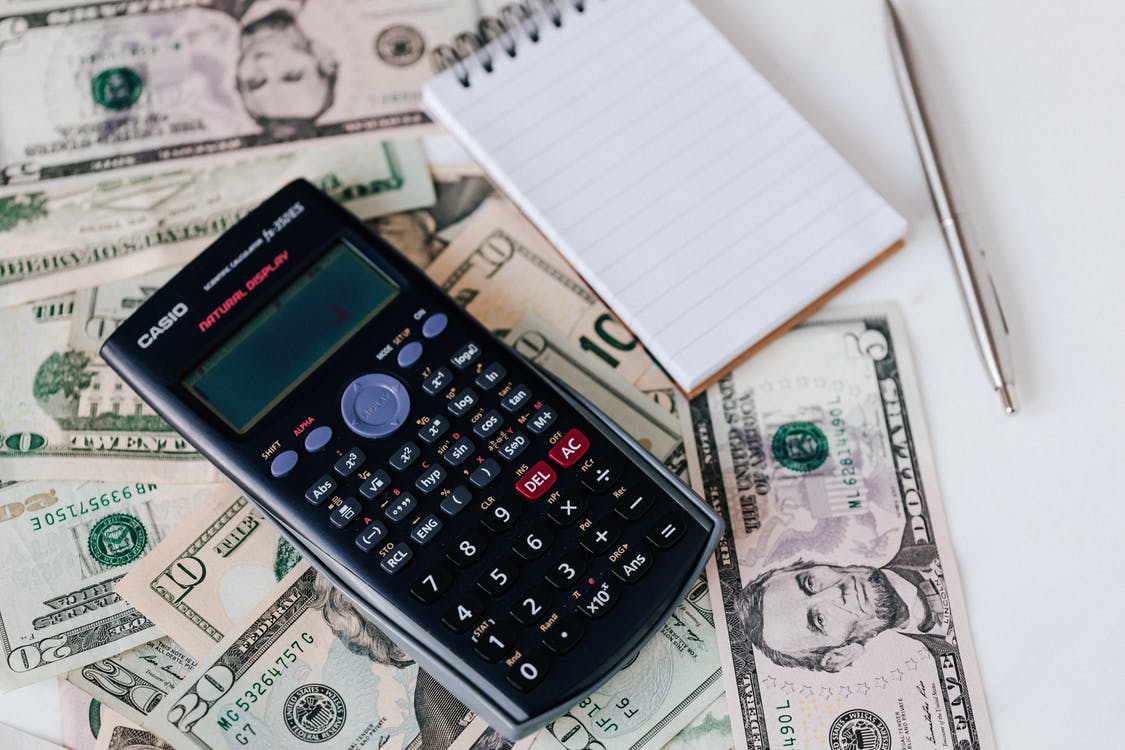 calculator and a notebook on top of money