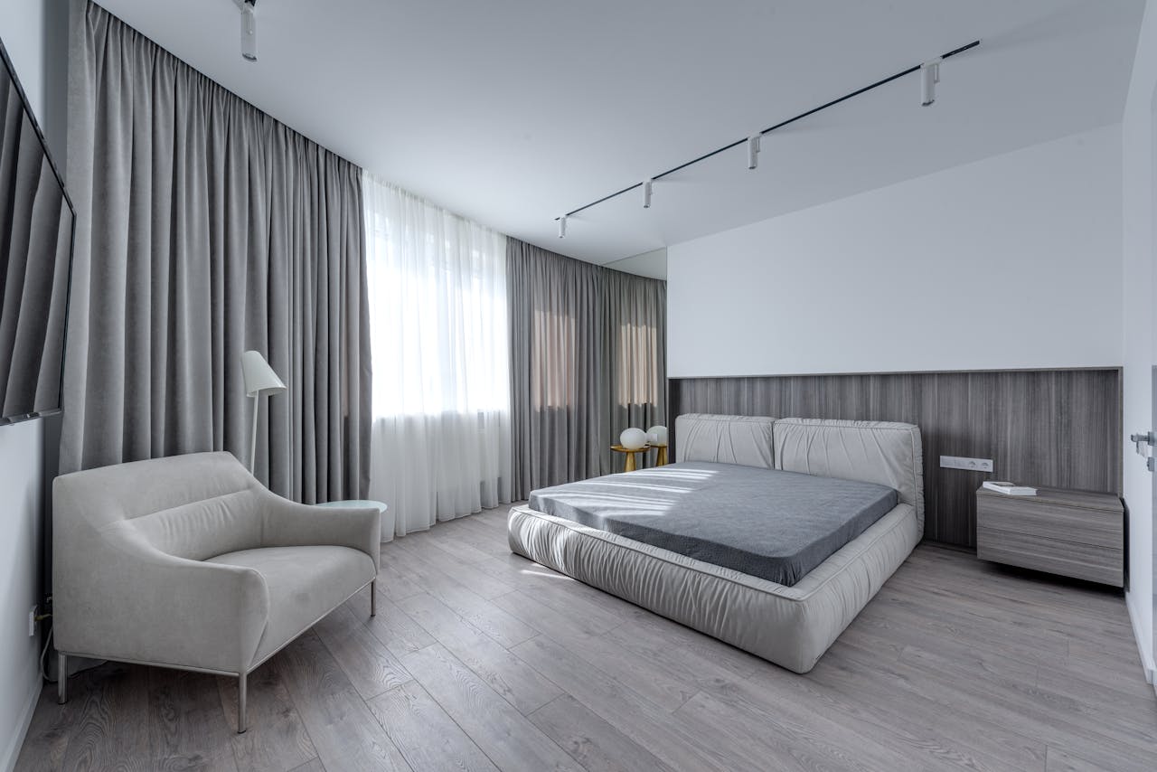 Spacious bredroom with grey curtains. Image by Pexels