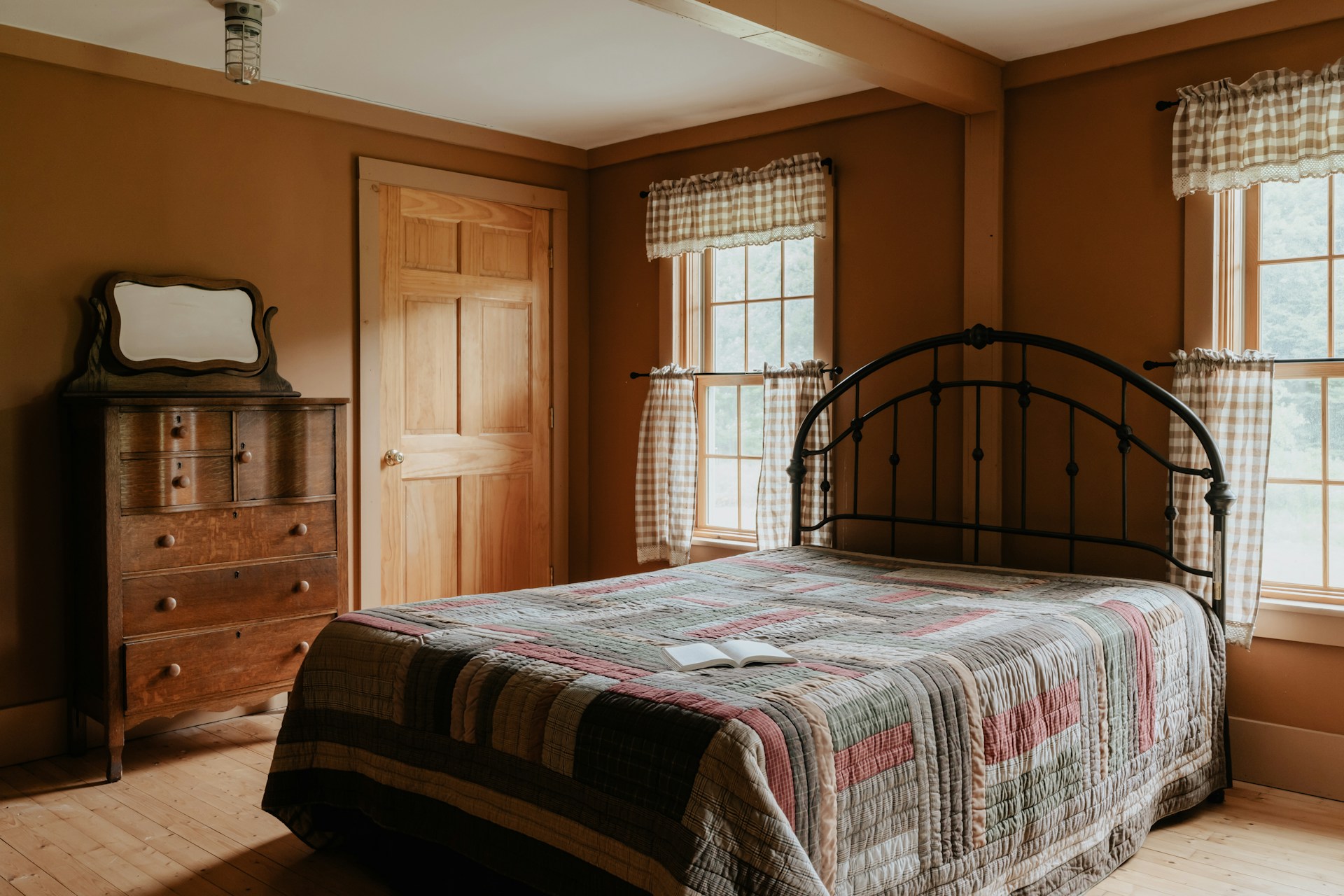 A bed sitting in a bedrom between two windows. Image by Unsplash