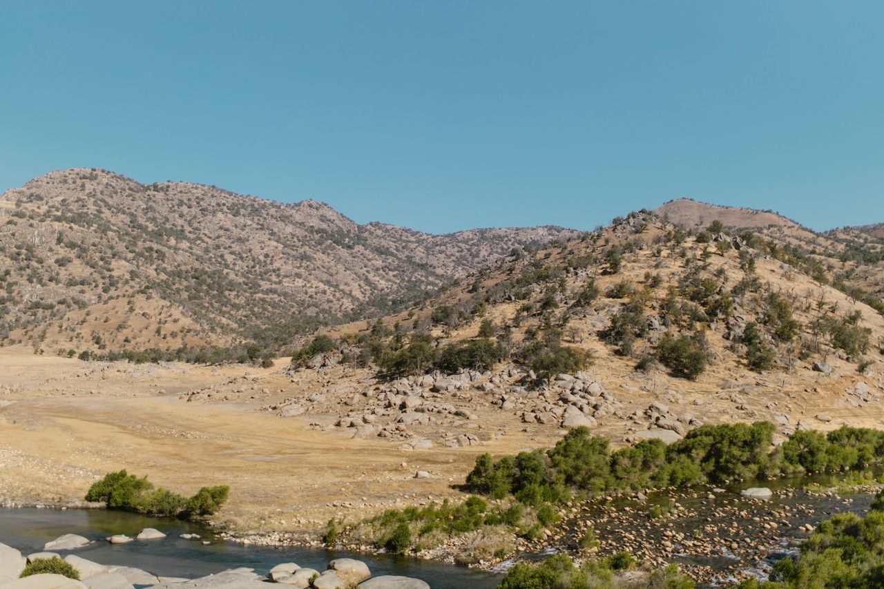 Arid landscape featuring rolling hills and sparse vegetation under a clear sky. Image by Pexels