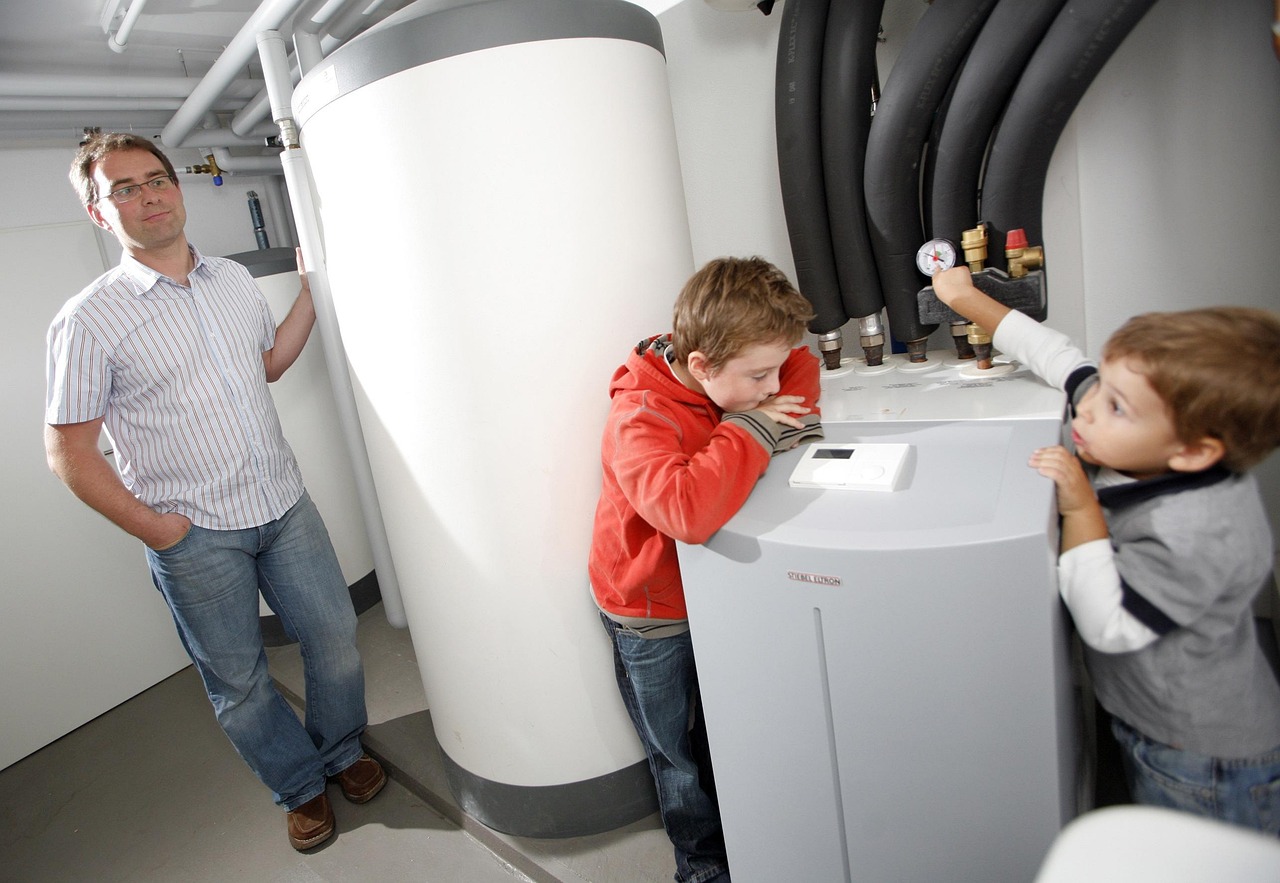 A father and his children looking at a heat pump unit outside their home. Image by Pixabay