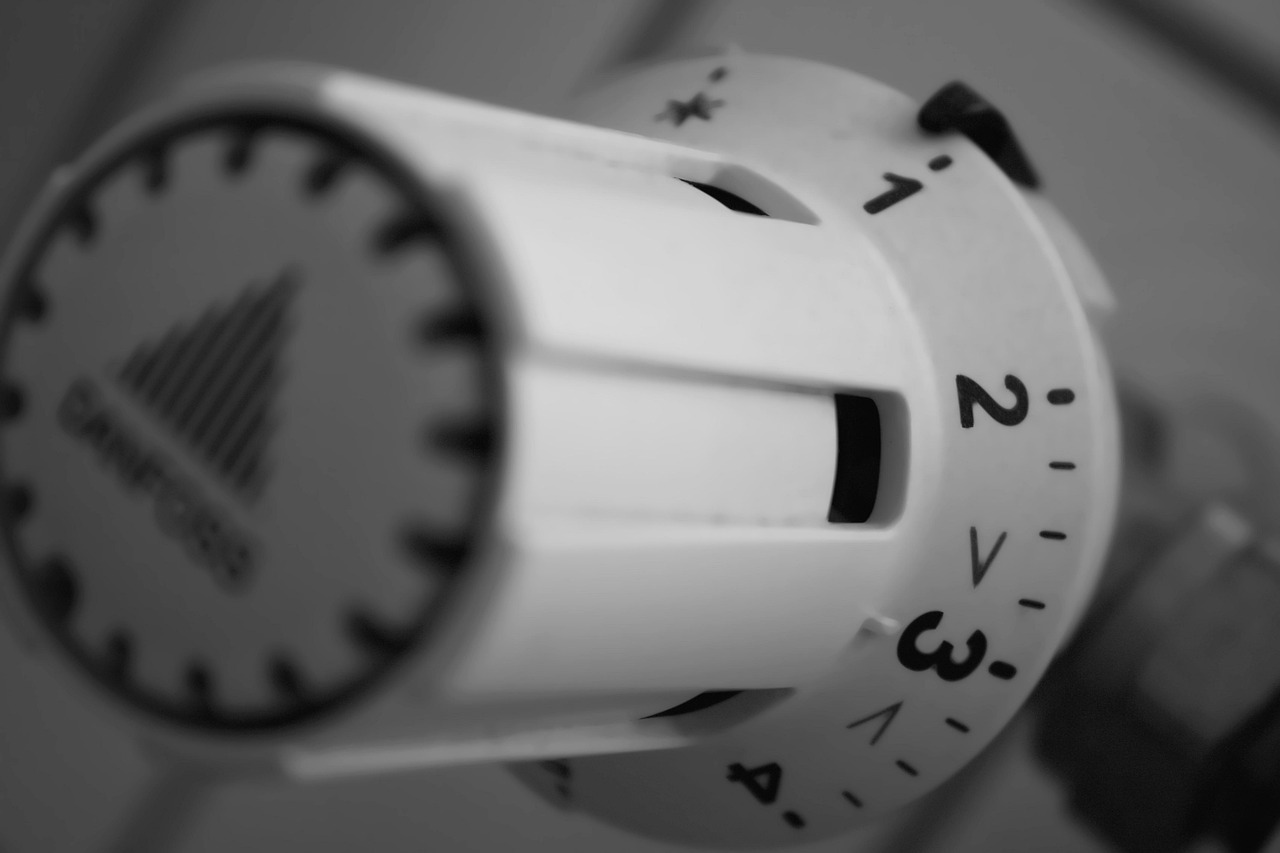 Hand adjusting a temperature controller during winter energy planning. Image via Pixabay