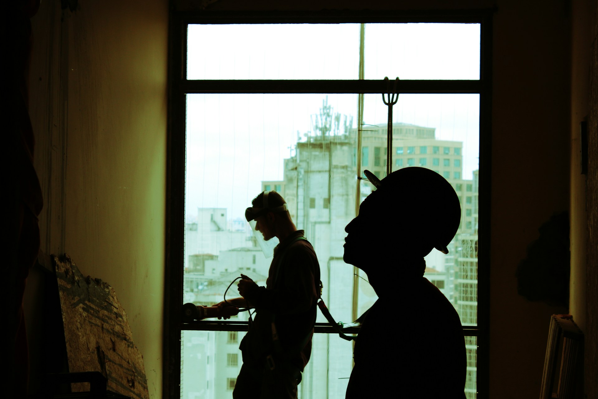 Two men wearing hard hats standing near a clear glass window. Image by Unsplash