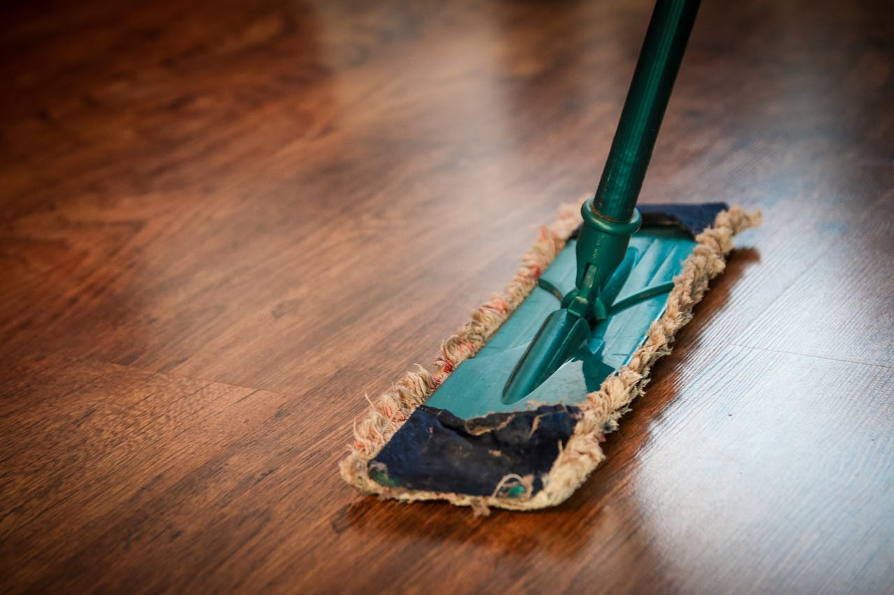 Brown wooden floor with a mop. Image by Pexels