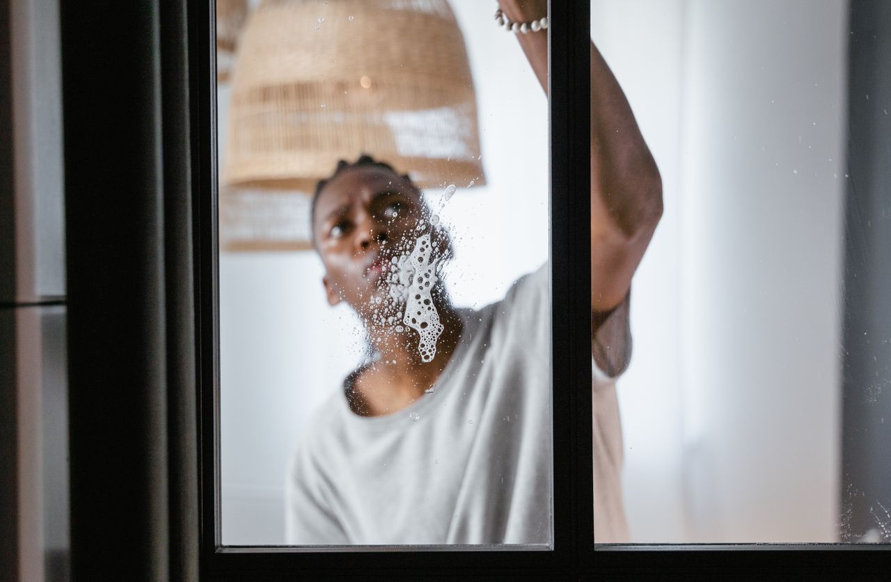 Person washing windows of an older Boston apartment. Image by Pexels