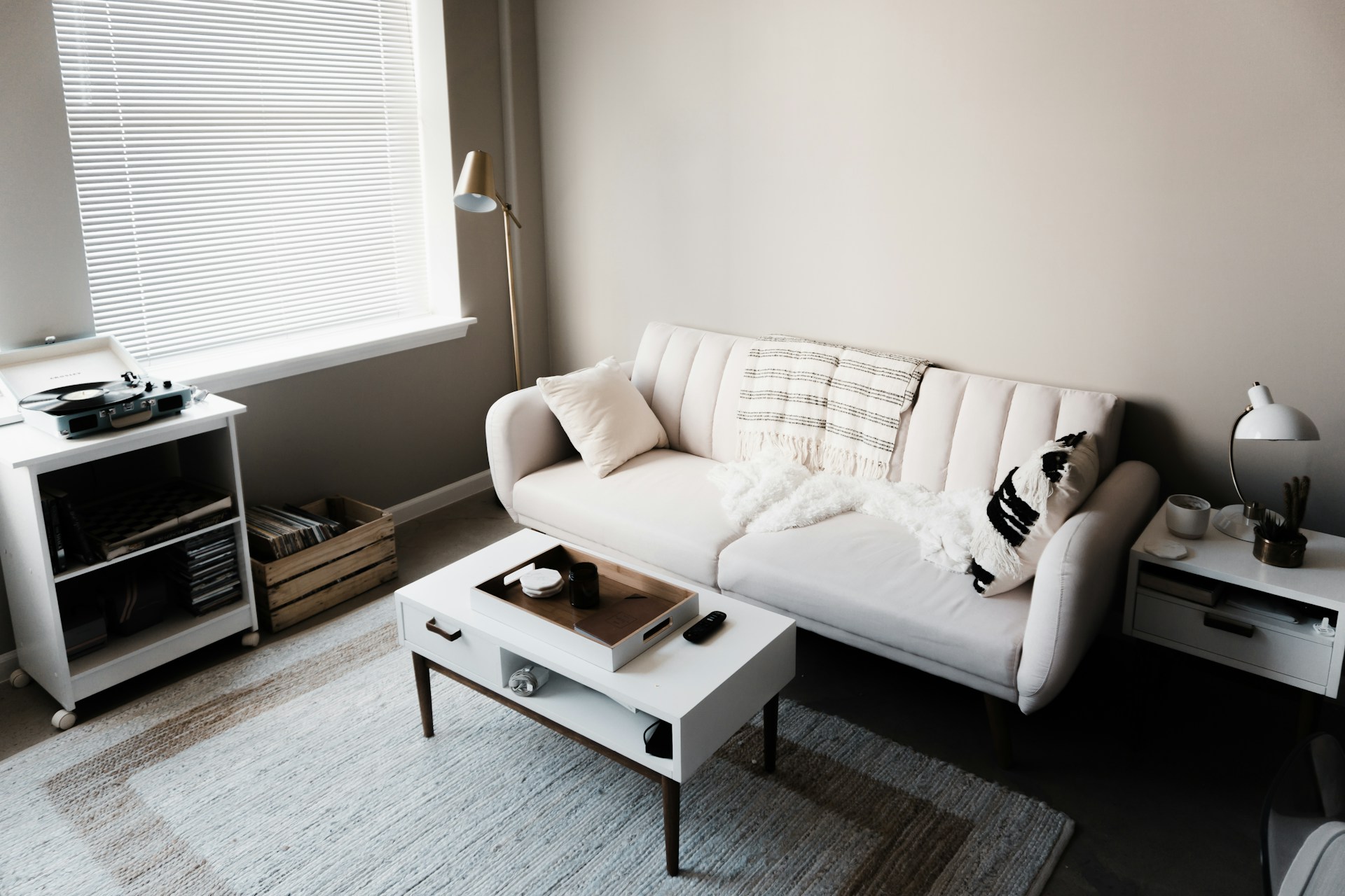 Livingroom, white couch in front of white wooden table. Image by Unsplash