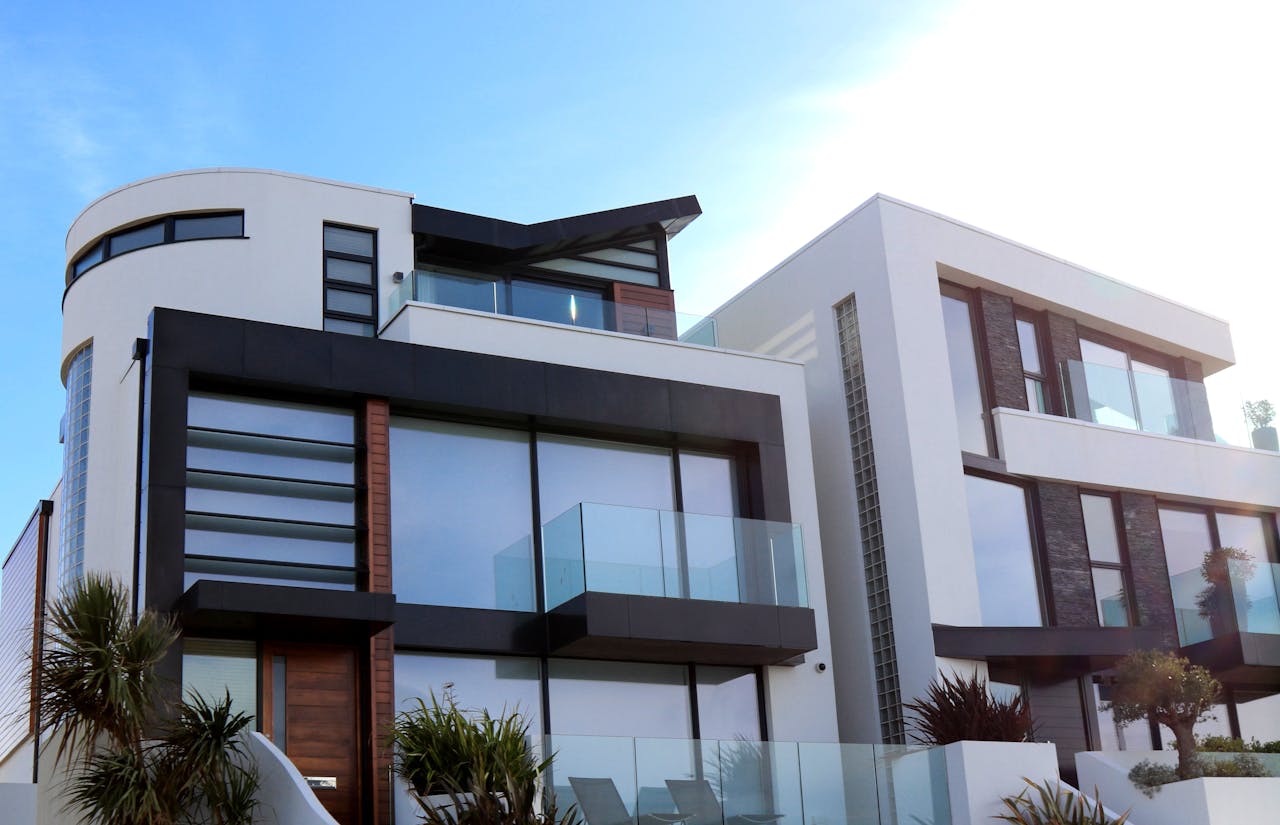 Modern white building, glass balconies, blue sky. Image by Pexels