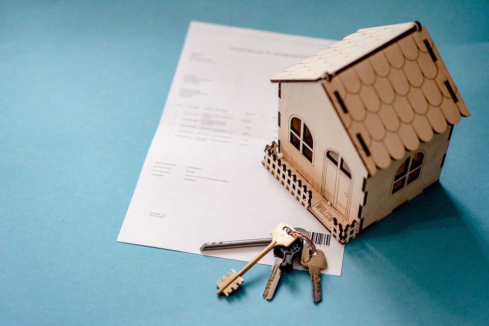 small wood house, keys, paper on table