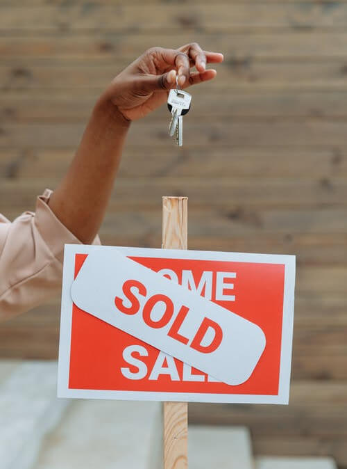 Holding keys over a sold sign