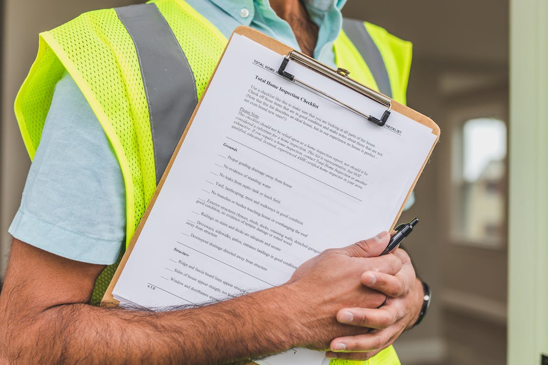 Photo of a person in a high-vis jacket holding a property inspection checklist as a featured image for a post titled 'how often should landlords inspect their rental properties.'