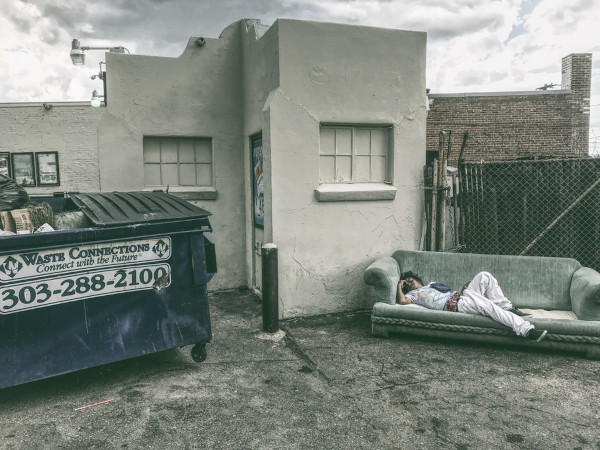 Dumpster in front of a house, person laying on a sofa